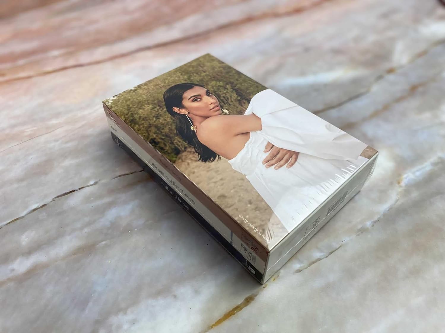 Rupi Kaur poetry book featured in soft portrait-style scene with feminine tones