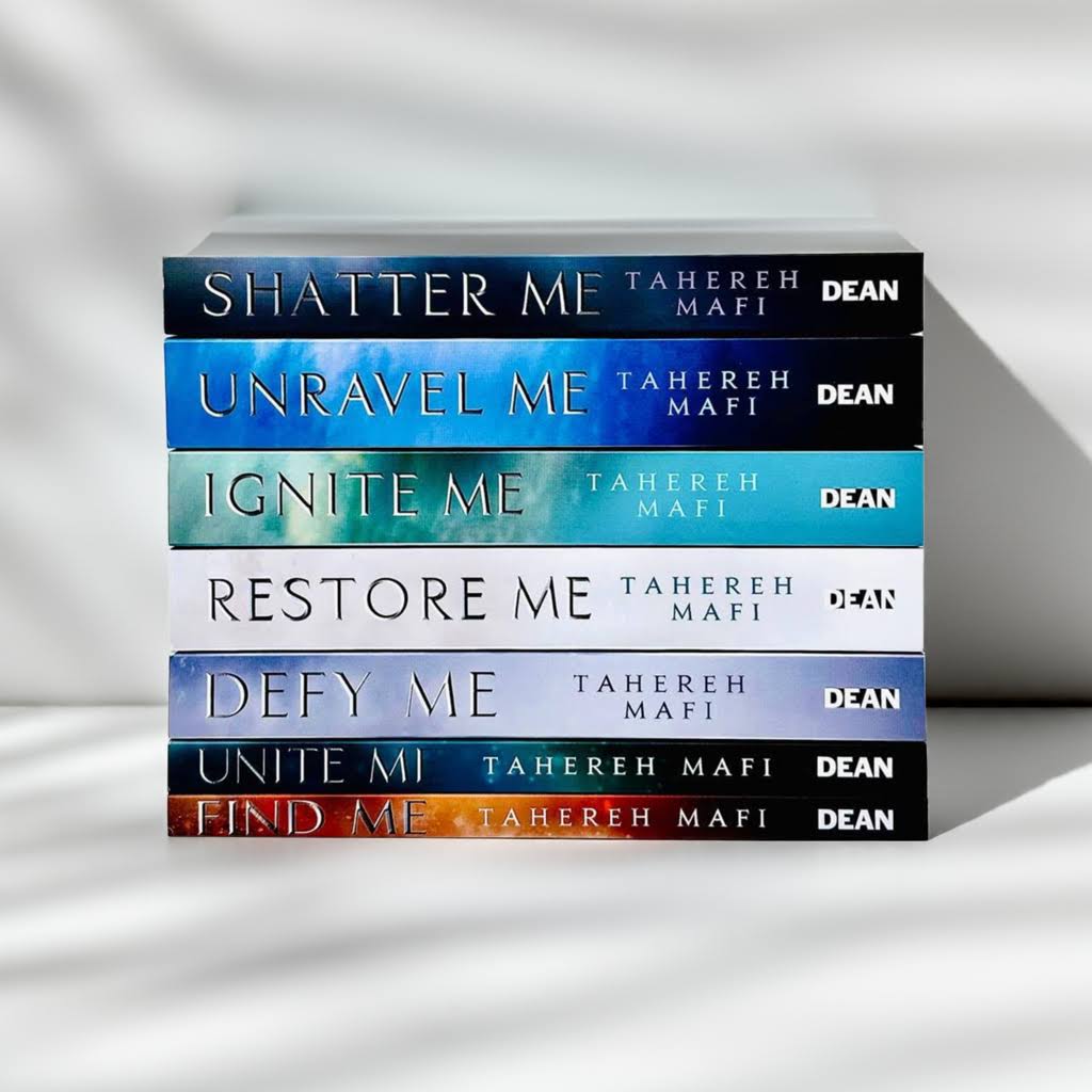Horizontal stack of the full Shatter Me series 1–7 by Tahereh Mafi on a white studio surface with soft shadows and clean background