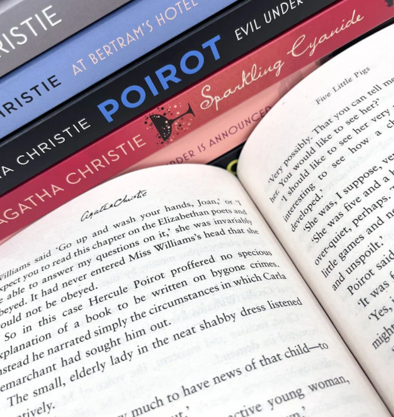 Open book with Agatha Christie's text, featuring a stack of books on top.