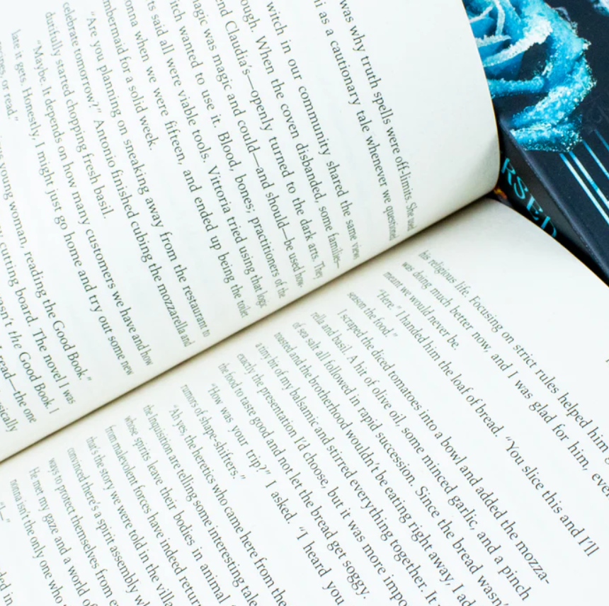 Open book with text and a blue flower on a black background