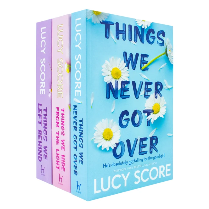 Three paperback books from the 'Things We Never Got Over' series by Lucy Score, shown in a fan-out arrangement. The front book is light blue with white daisies and blue title text, while the two books behind it are lavender and pink respectively.