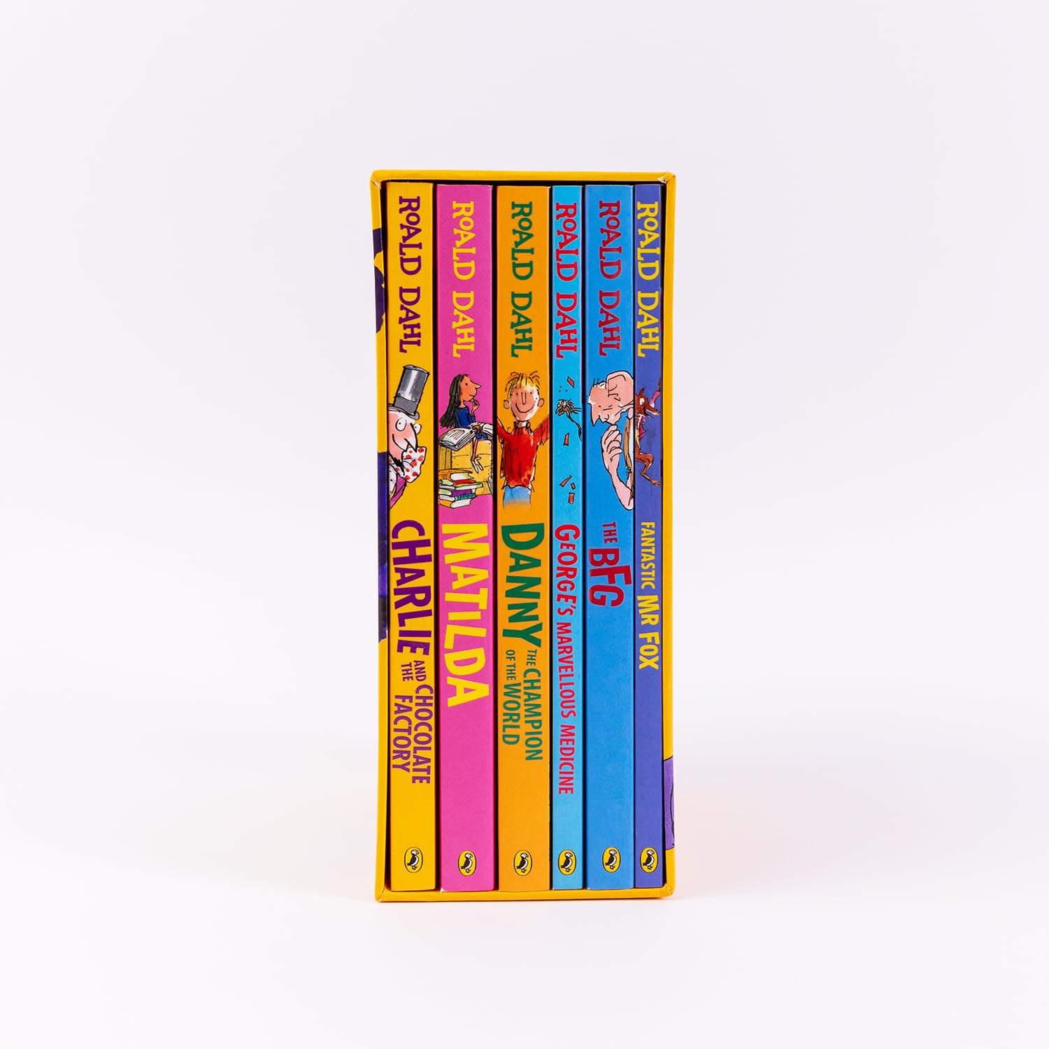 A boxed set of six children's books by Poul Dahl and Charlie and the Chocolate Factory, standing upright against a clean white background. The books feature bright, colorful spines in yellow, pink, orange, blue, and purple with illustrated covers and visible Penguin logos at the bottom.