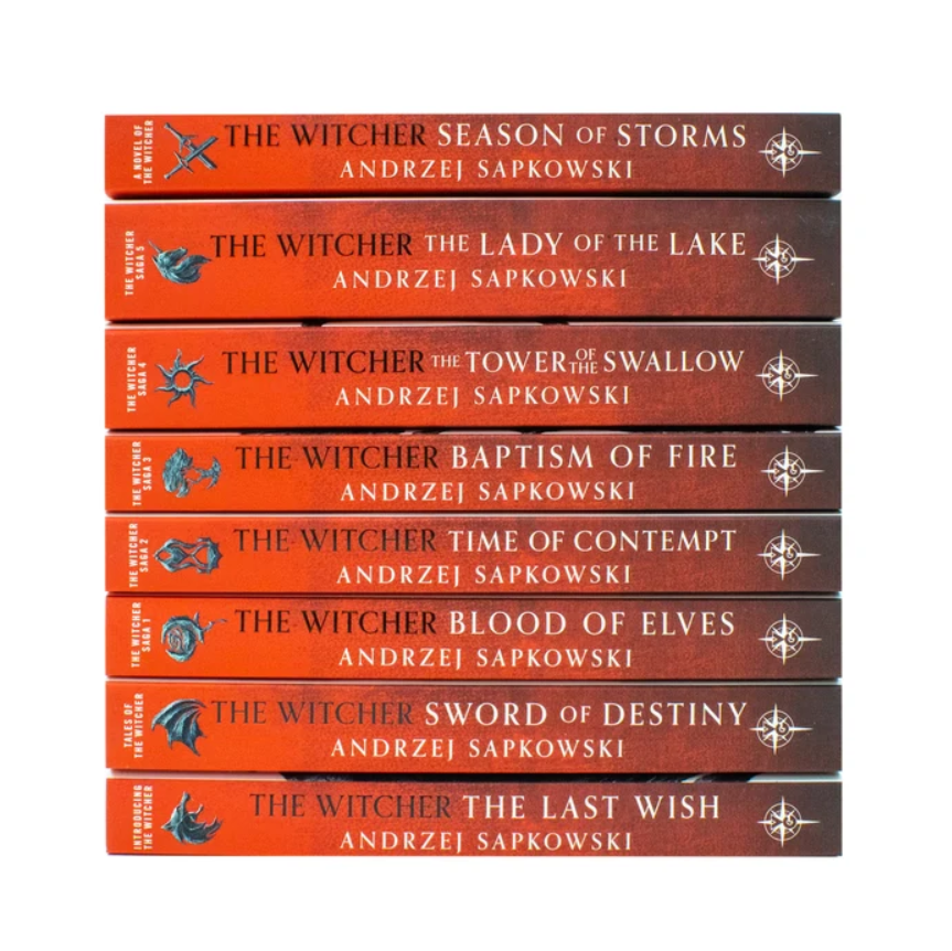 A stack of ten hardcover books of The Witch series by Andrzej Sapkowski, showing the orange-red spines with white text and blue winged symbols.