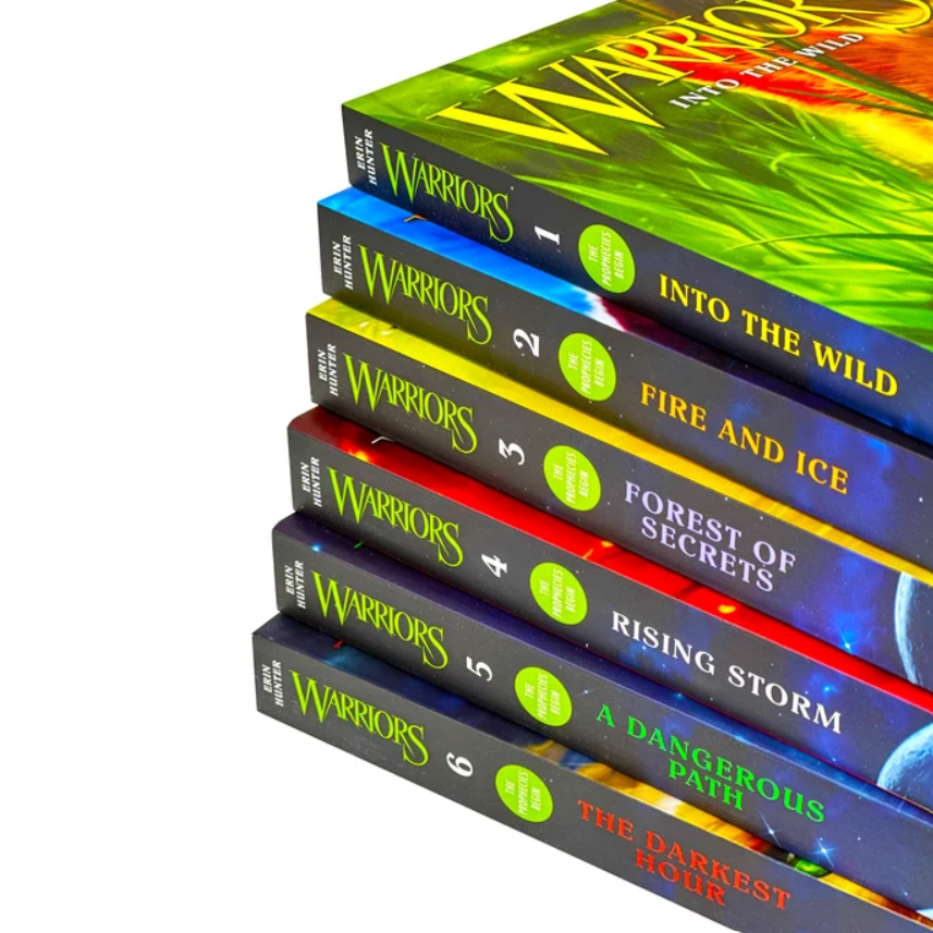 A stack of six hardcover books from the Warriors series, titled Into the Wild, Fire and Ice, Forest of Secrets, Rising Storm, A Dangerous Path, and The Darkest Hour, shown on a clean white background.